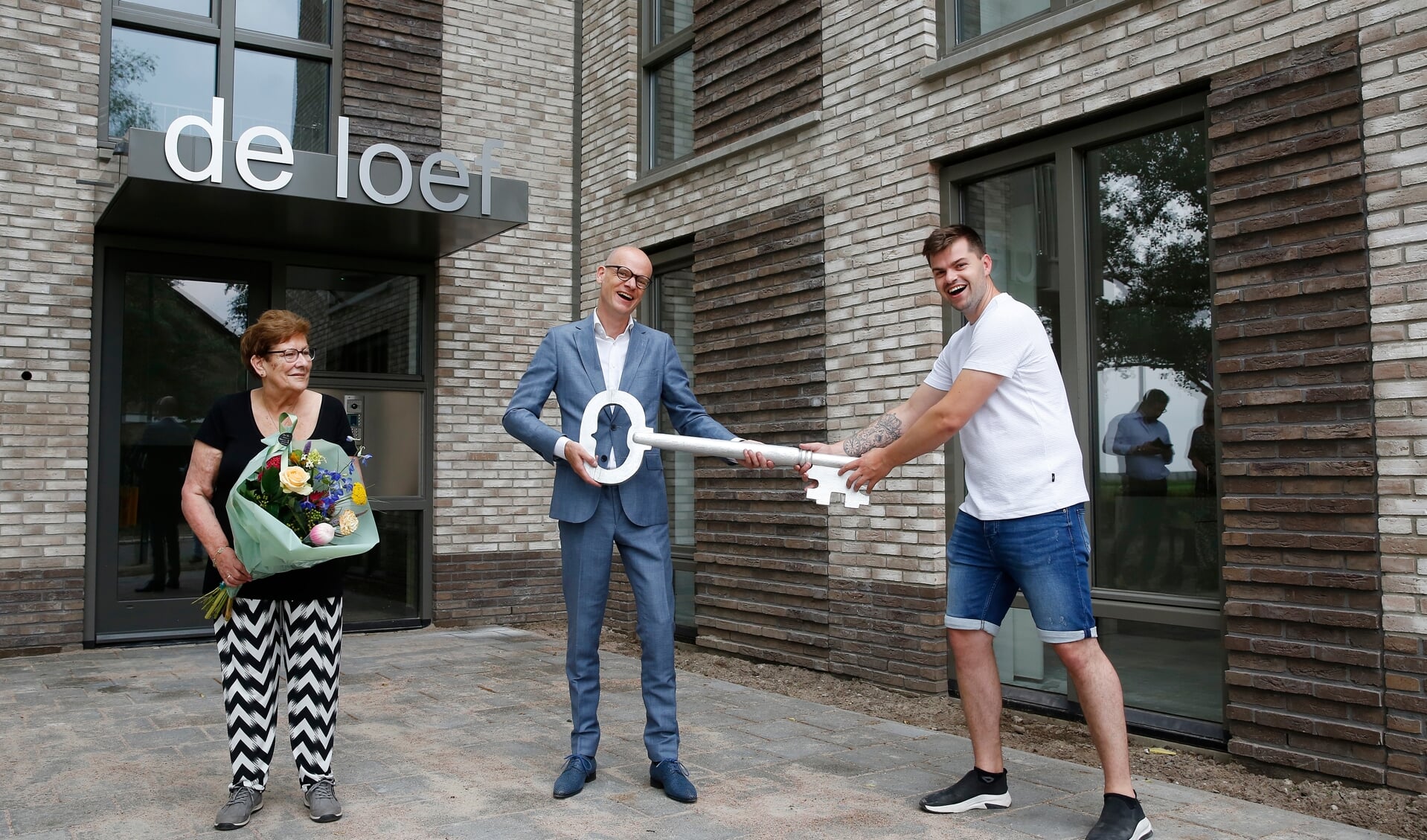 Directeur-bestuurder François Claessens (midden) reikt een sleutel uit aan twee bewoners van De Loef.