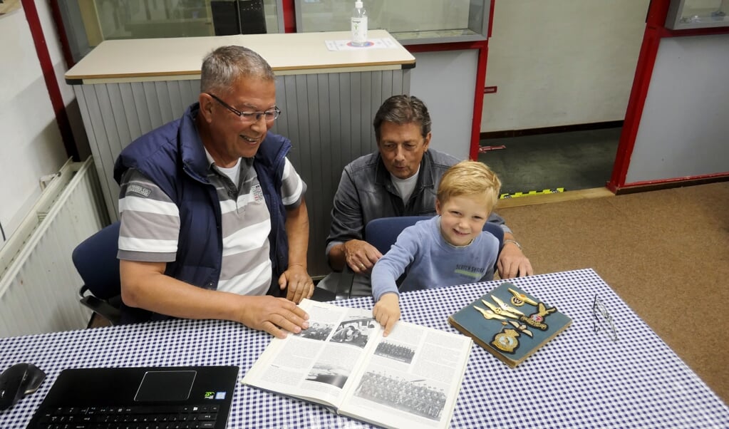 Rick Franke (links) ontvangt een logboek van piloot Jaymes Kuyper, geschonken door diens kleinzoon Bill Kuyper. Het kleine jochie heet Jaymes, zijn achterkleinzoon. 