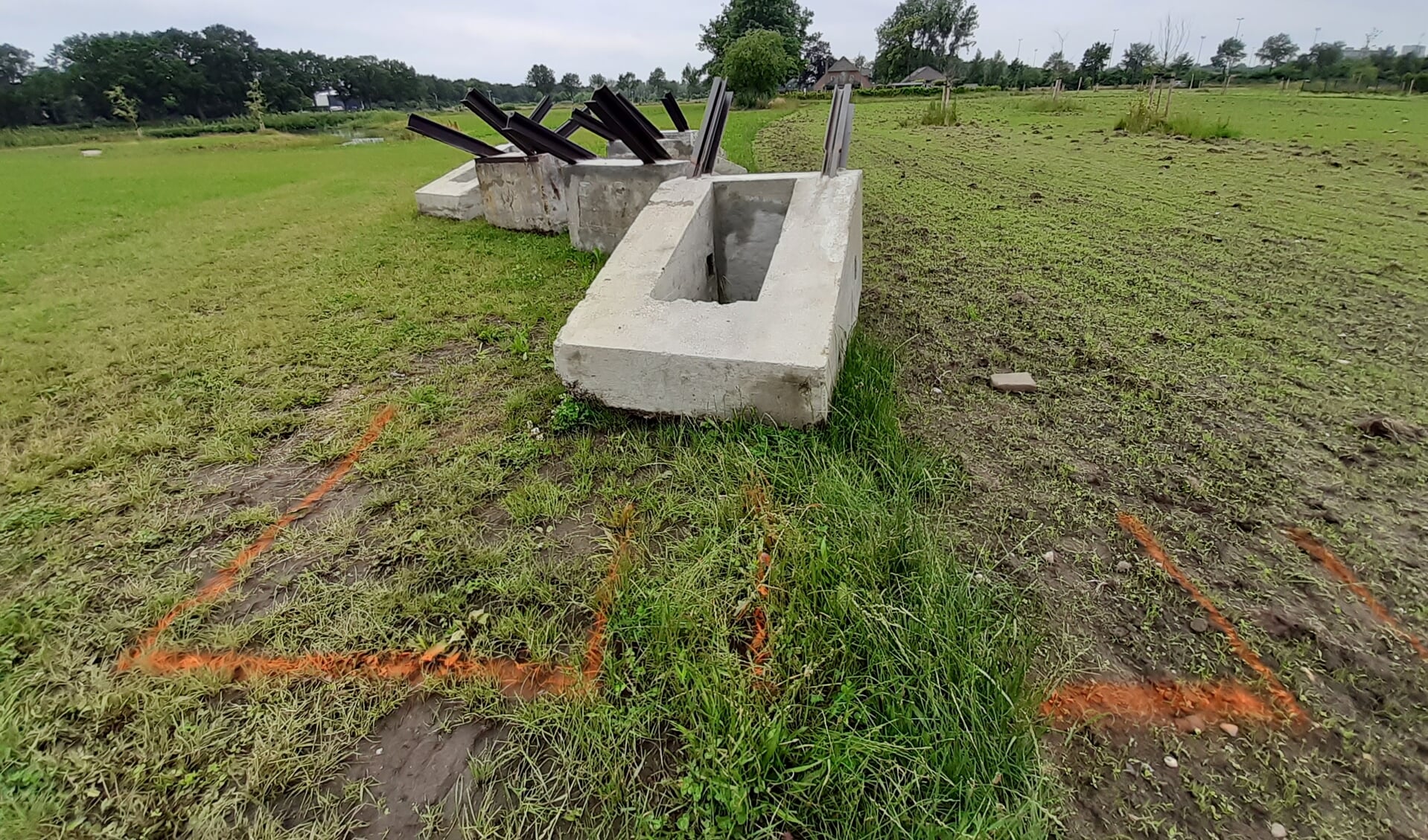 De gerestaureerde betonnen tankversperringen liggen te wachten tot ze worden ingegraven. Op de grond is al aangegeven waar ze moeten komen.