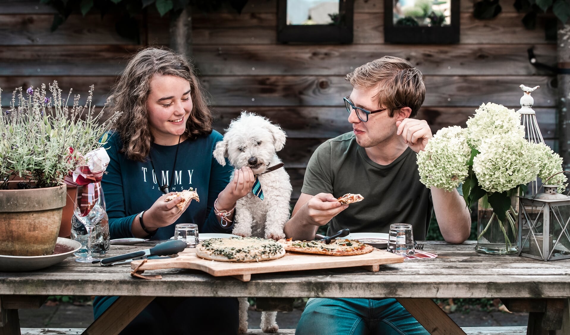 Lilian van den Brink en Caspaer van Garderen (19) uit Woudenberg genieten in Harskamp van een pizza  na aan lange wandeltocht voor het goede doel. In het midden hun twaalfjarige Maltezer-hondje Benji.