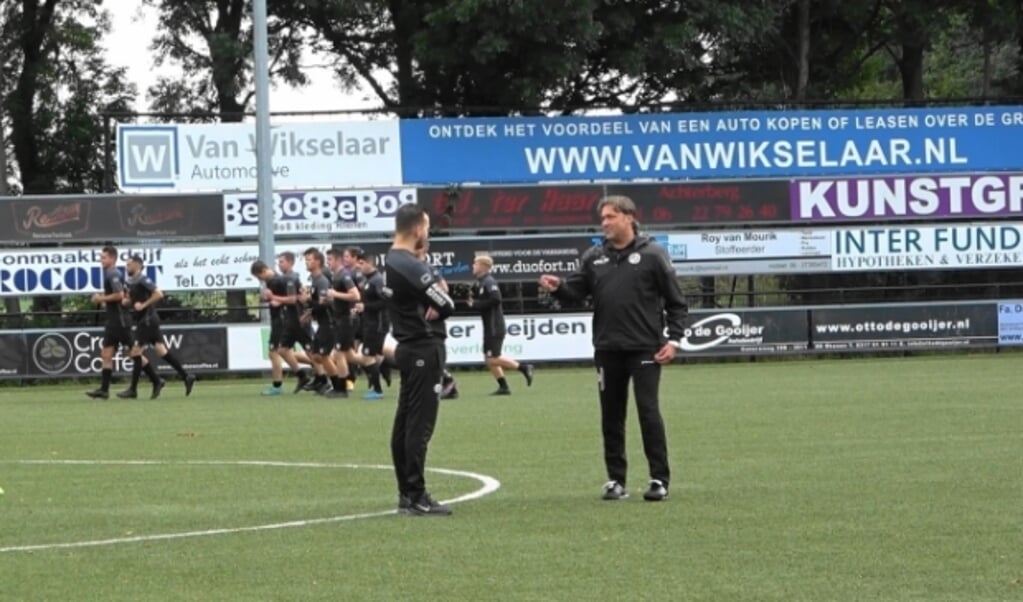 Jan Veldhuizen in gesprek met Dion van der Laan met op de achtergrond een gedeelte van de VVA selectie 2021/2022.