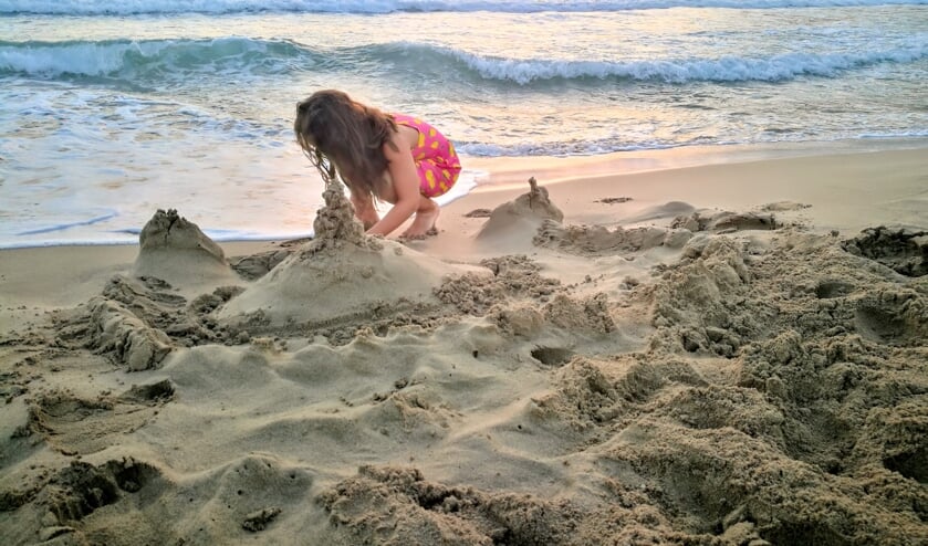 ,,Dit is onze dochter Nikki van acht die druk en geconcentreerd een zand dorp aan het maken was.Eind middag, strand Nikolaos in het dorpje Arkassa, eiland Karpathos, Griekenland."