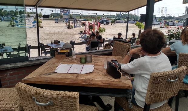 Het publiek geniet vanaf het terras van de paardensport