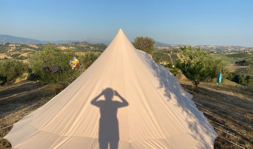 ,,Je ziet mij als silhouet terwijl ik een foto maak van onze tent (& onze handdoeken..;) in de ochtendzon in Italië, waar we kampeerden op een mini-camping/agriturismo, bovenop de heuvel, midden tussen de olijfbomen, in Monsampolo del Tronto, met uitzicht op de Sibillijnse bergen en de Adriatische zee. Er heerste helaas een hittegolf, dus om 7.00u brandde je je tent uit, maar het uitzicht was magnifiek!"