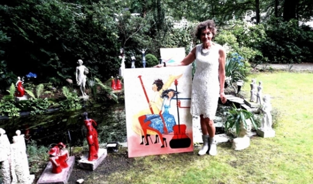 Denise Wouters, met een van haar haar jongste schilderijen in haar beeldentuin