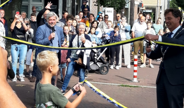 <p>Burgemeester Verhulst 'opent' de poort, geholpen door twee basisschoolleerlingen.</p>