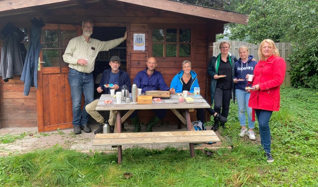 Een aantal van de vrijwilligers geniet van koffie met pruimentaart bij de nieuwe berging in de buurtboomgaard.