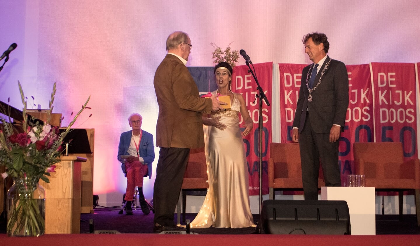 Burgemeester Verhulst krijgt een gouden doos aangereikt, met daarin het nieuwe Jubileumboek van De Kijkdoos