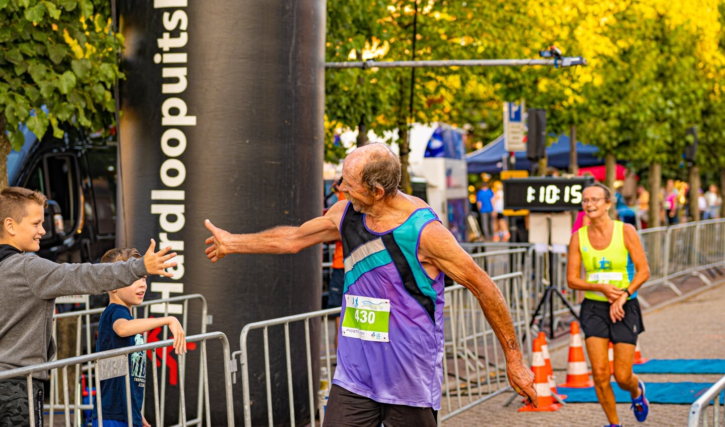 Tom Hameeteman won de fotowedstrijd van Bunniks Mooiste met deze foto van een loper die een high five geeft bij de finish.