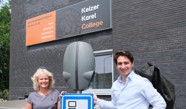 <p>Maxime van Gelder van EVBox en oud-leerling van het KKC overhandigt de laadstations aan docent Sietske Roos, </p>
