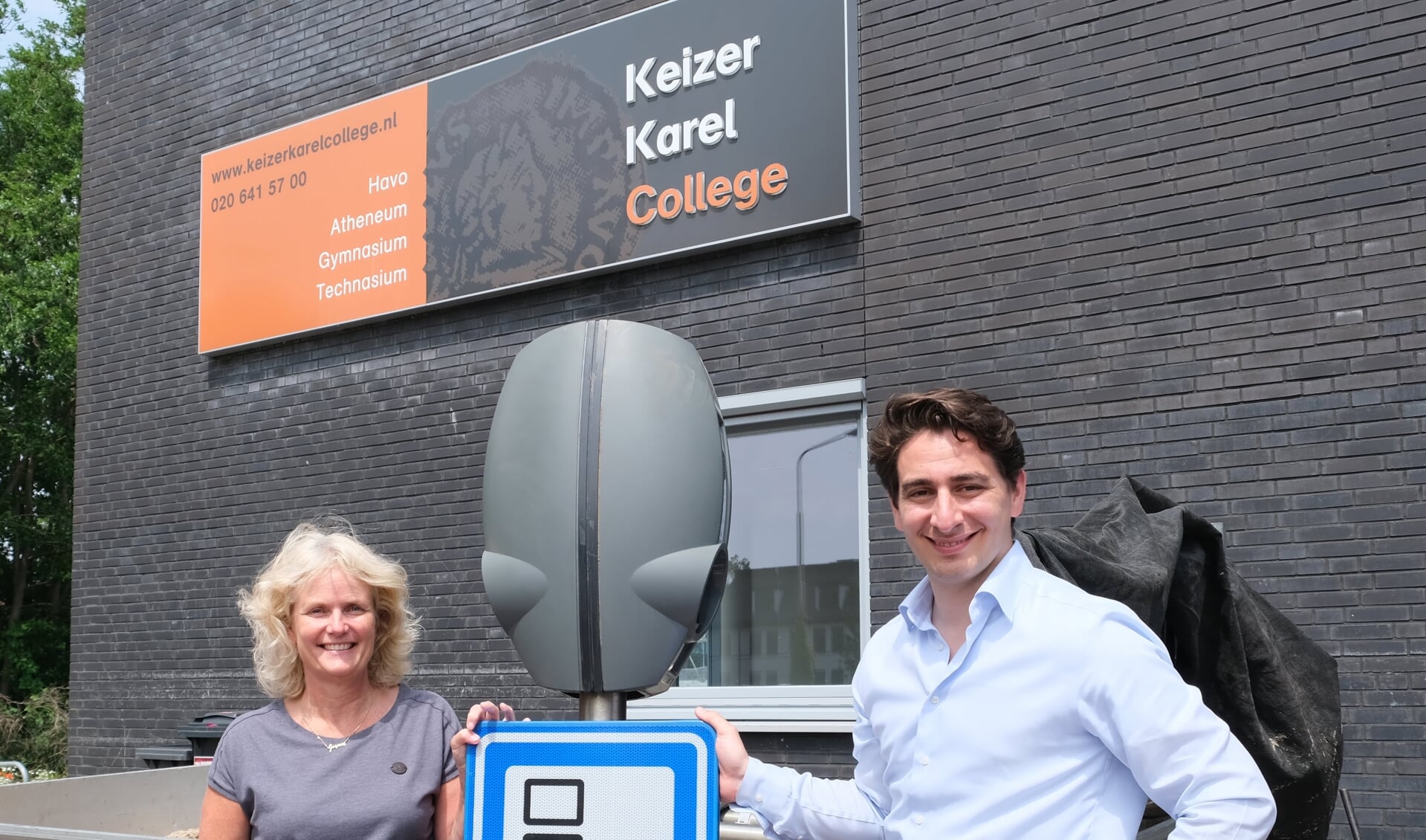 Maxime van Gelder van EVBox en oud-leerling van het KKC overhandigt de laadstations aan docent Sietske Roos, 