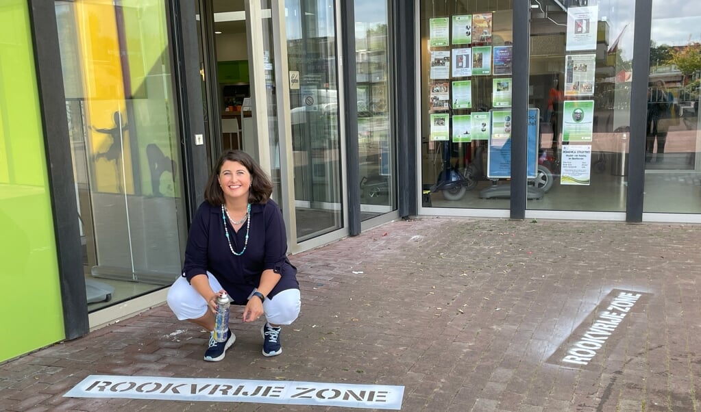 Wethouder Barbara de Reijke maakt rookvrij zone zichtbaar bij het Dorpshuis in Duivendrecht.