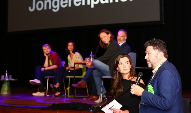 <p>Fleur Huijs in gesprek met wethouder Jur Botter, op de achtergrond het jongerenpanel.</p>