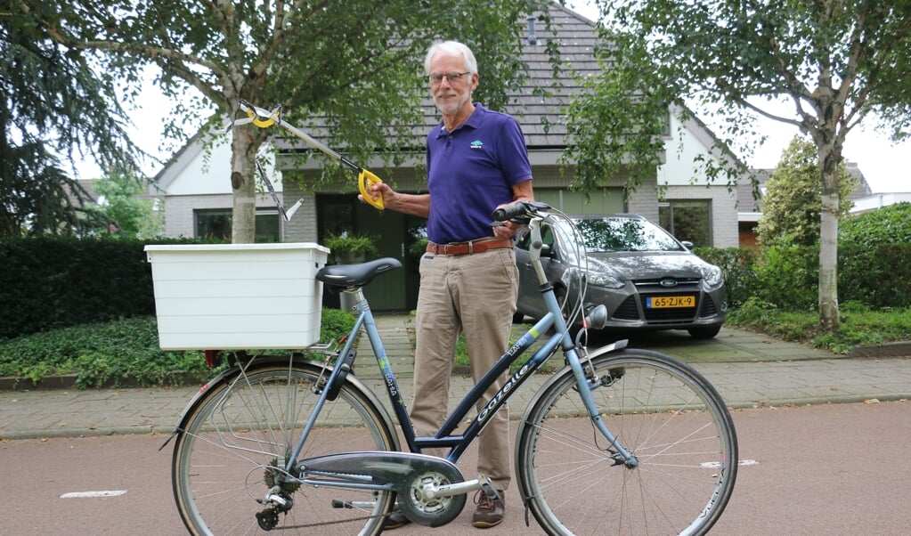 Huib van Weelden met zijn speciale fiets, met bak en een zerfvuilgrijper.