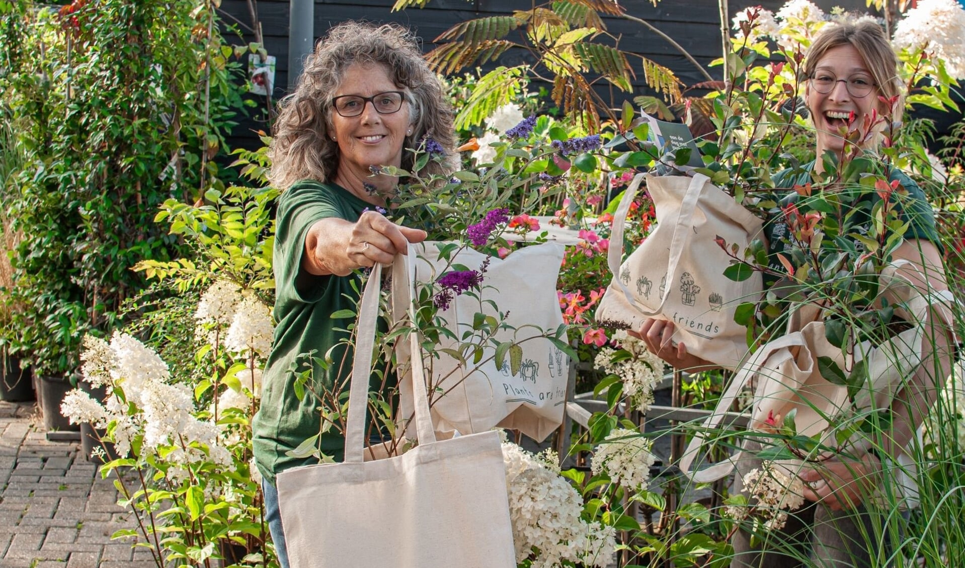 Petra Ekhardt (l) en Corienne Merkens van Merkens Tuincentrum met de gratis planten in canvas tassen, die worden aangeboden tijdens de actie ‘Tegel eruit, plant erin’. 