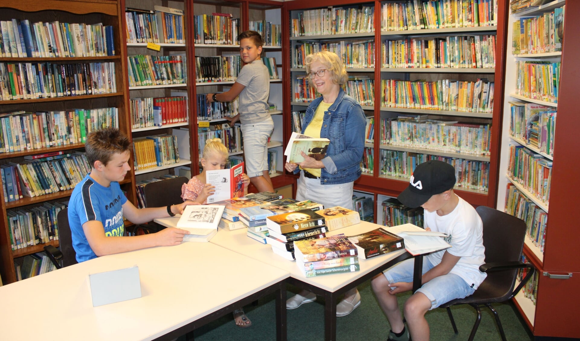 Reina Hootsen in de kleine Bethelbibliotheek in Achterberg, omringd door jeugdige lezers.