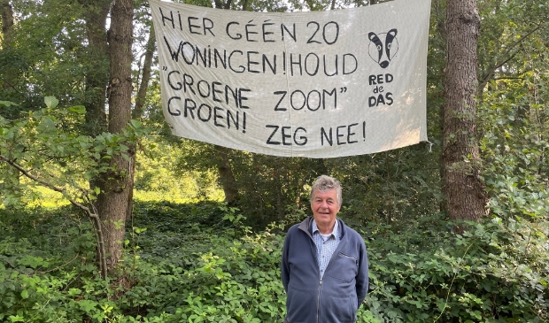 Projectontwikkelaar Peter Siccama onder het spandoek van de tegenstanders van zijn ontwikkelproject.