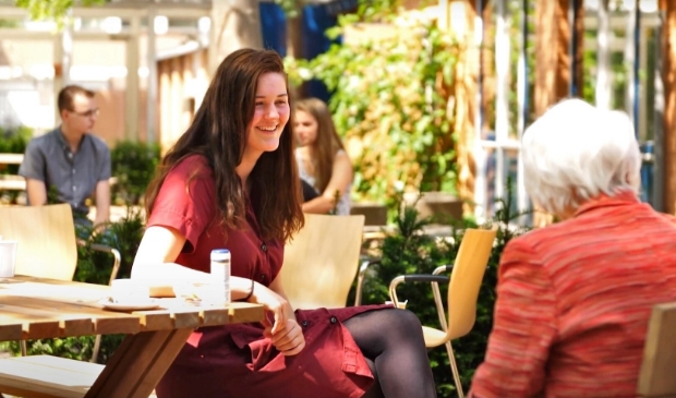 Jong en oud met elkaar in gesprek tijdens een generatiegesprek in de tuin van verbinding bij de EH