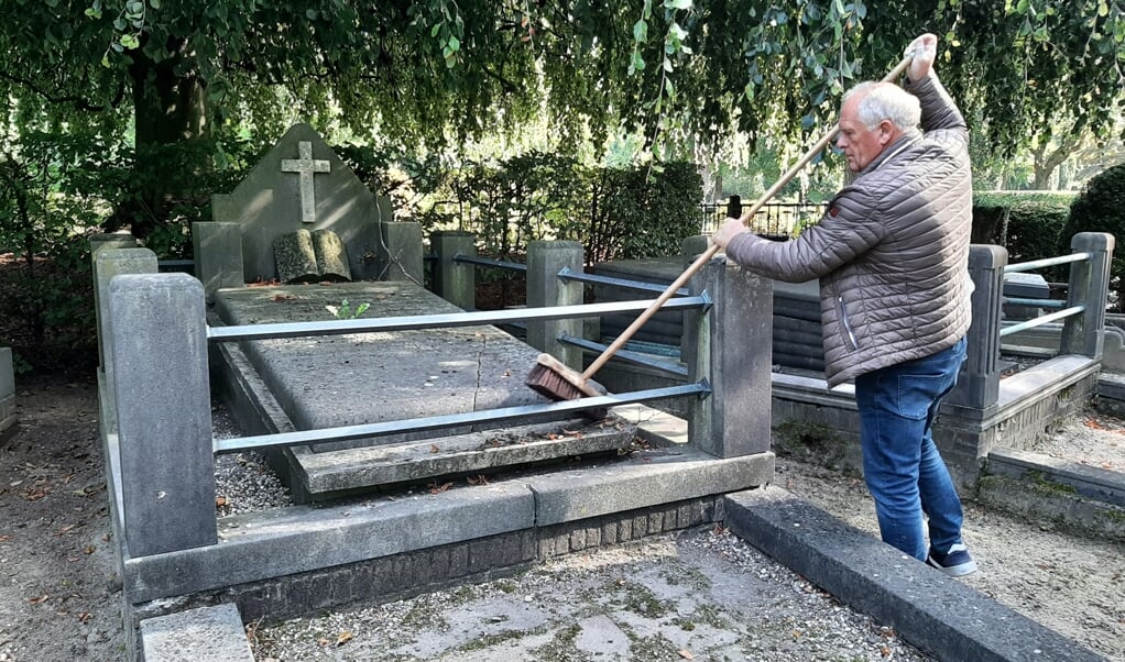 Aart Aalbers bij het graf van dominee Jongebreur en zijn vrouw. Het graf moet nodig worden opgeknapt. Hij is alvast begonnen met het schoonvegen. 