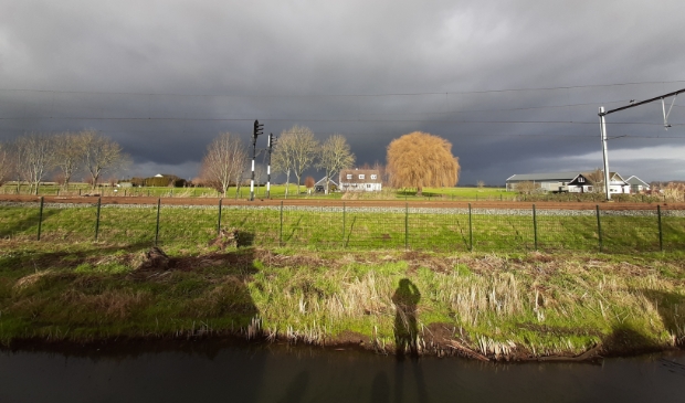 De contouren van de fotograaf door de laagstaande winterzon, met daarachter de Merwede Lingelijn en verder de polder achter de Spoorweg in Hardinxveld-Giessendam