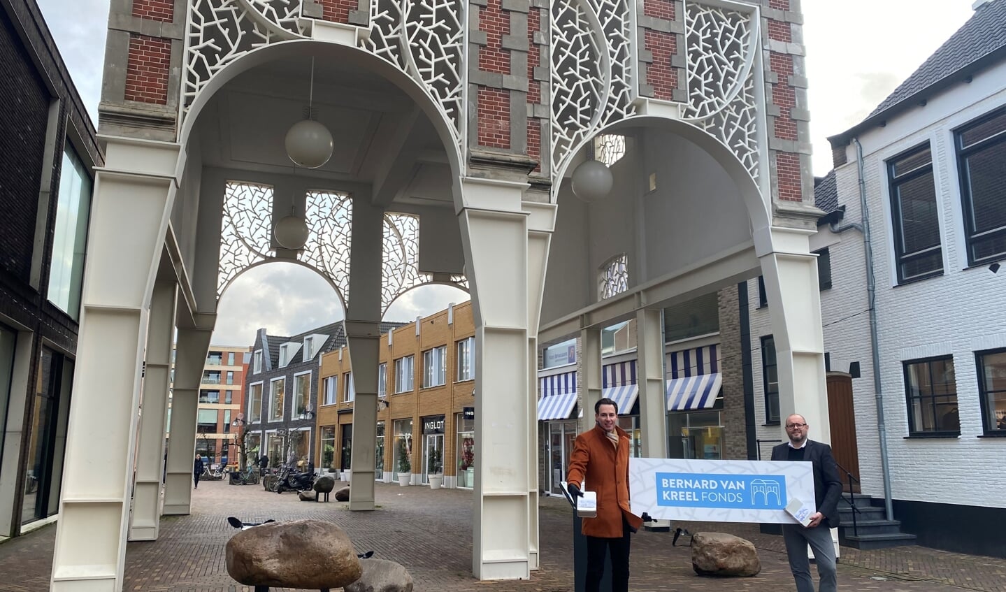 Wethouder Dylan Lochtenberg en binnenstadsmanager Henny Jansen presenteren het Bernard van Kreel-fonds bij de gelijknamige poort in het centrum van Veenendaal.