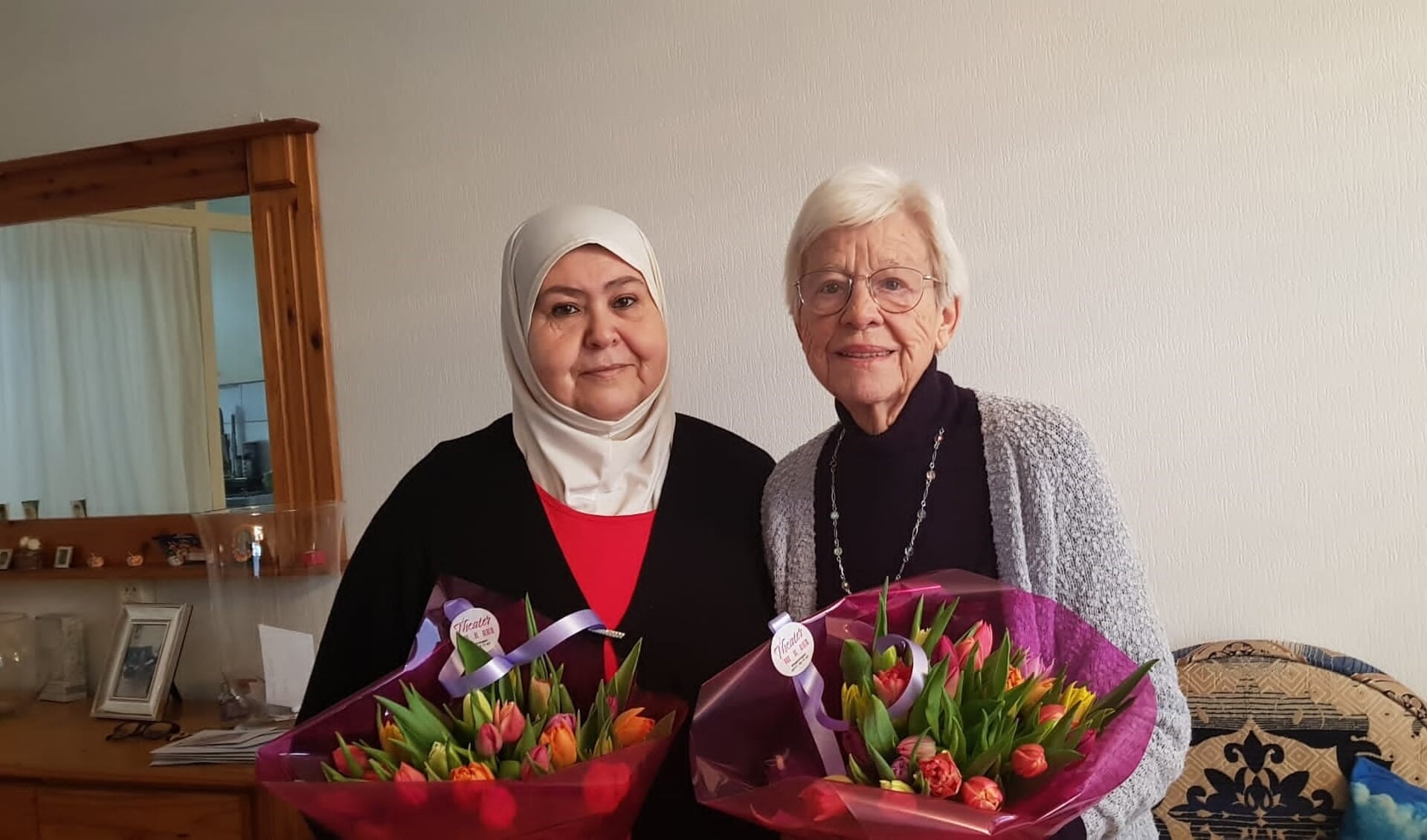 Zohra en Geertje ontvangen een bloemetje ter ere van hun 10-jarig jubileum
