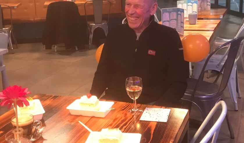 Henk Rademakers, lachend achter zijn champagne en gebak vanwege zijn 85e verjaardag