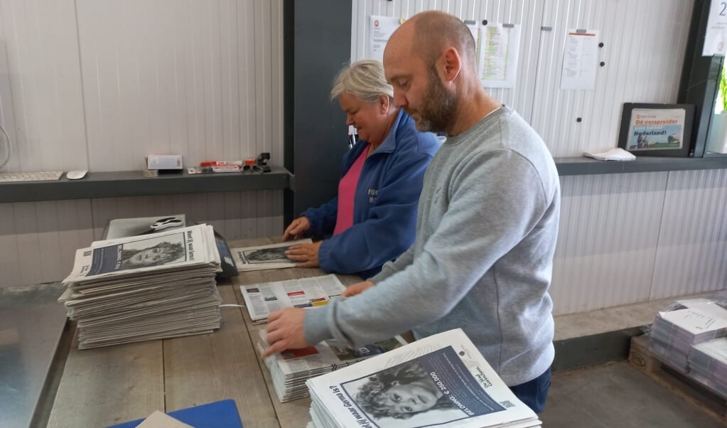 Alex Monster en Hannie Visser assisteren bij vouwen van de kranten over Germa