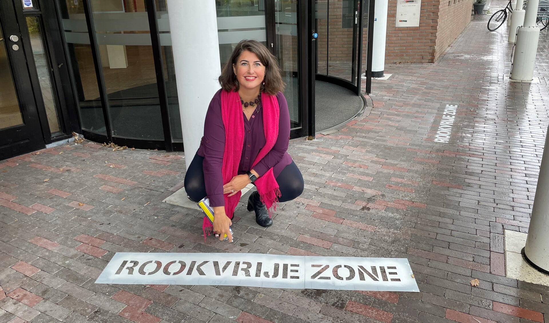 Wethouder Barbara de Reijke markeert rookvrij zone bij Gemeentehuis in Ouderkerk.
