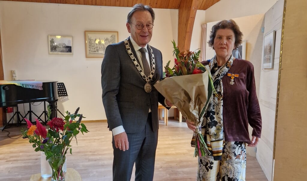 Burgemeester Koos Janssen heeft de onderscheiding opgespeld bij gouden vrijwilliger Ollif Smilda.