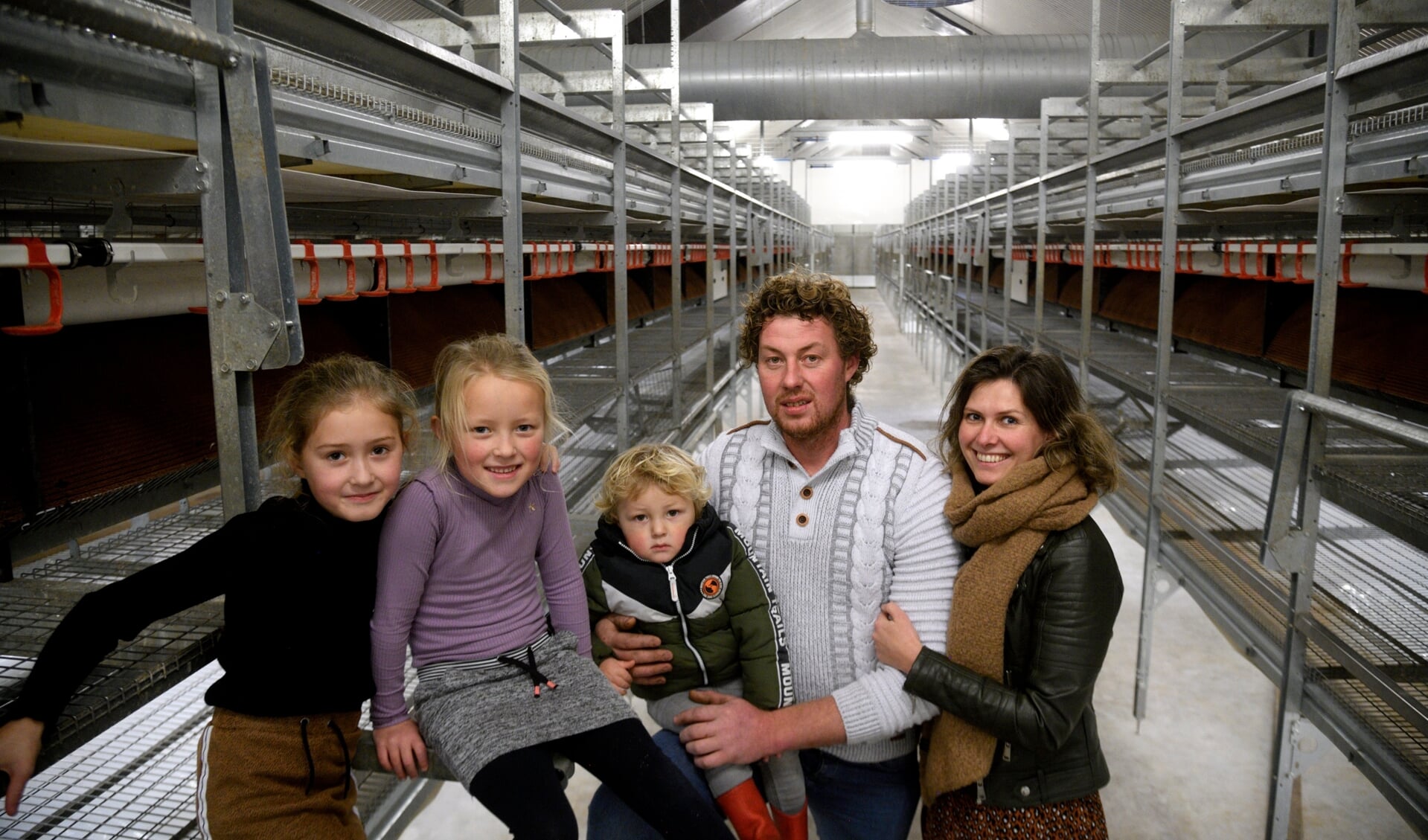 Maas en Rosanne van Harten met drie van hun vier kinderen in de preventief geruimde pluimveestal met plek voor 10.000 leghennen.