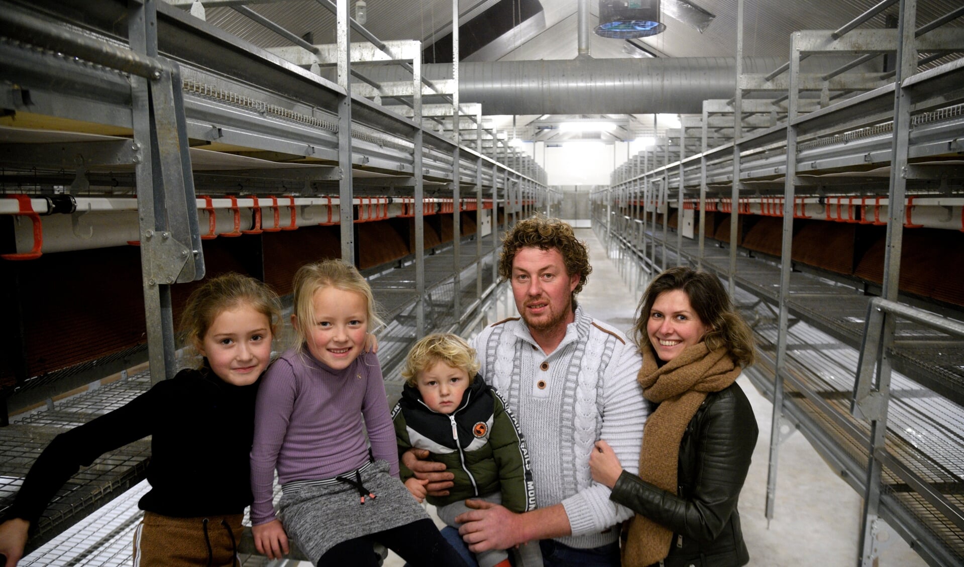 Maas en Rosanne van Harten met drie van hun vier kinderen in de preventief geruimde pluimveestal met plek voor 10.000 leghennen.