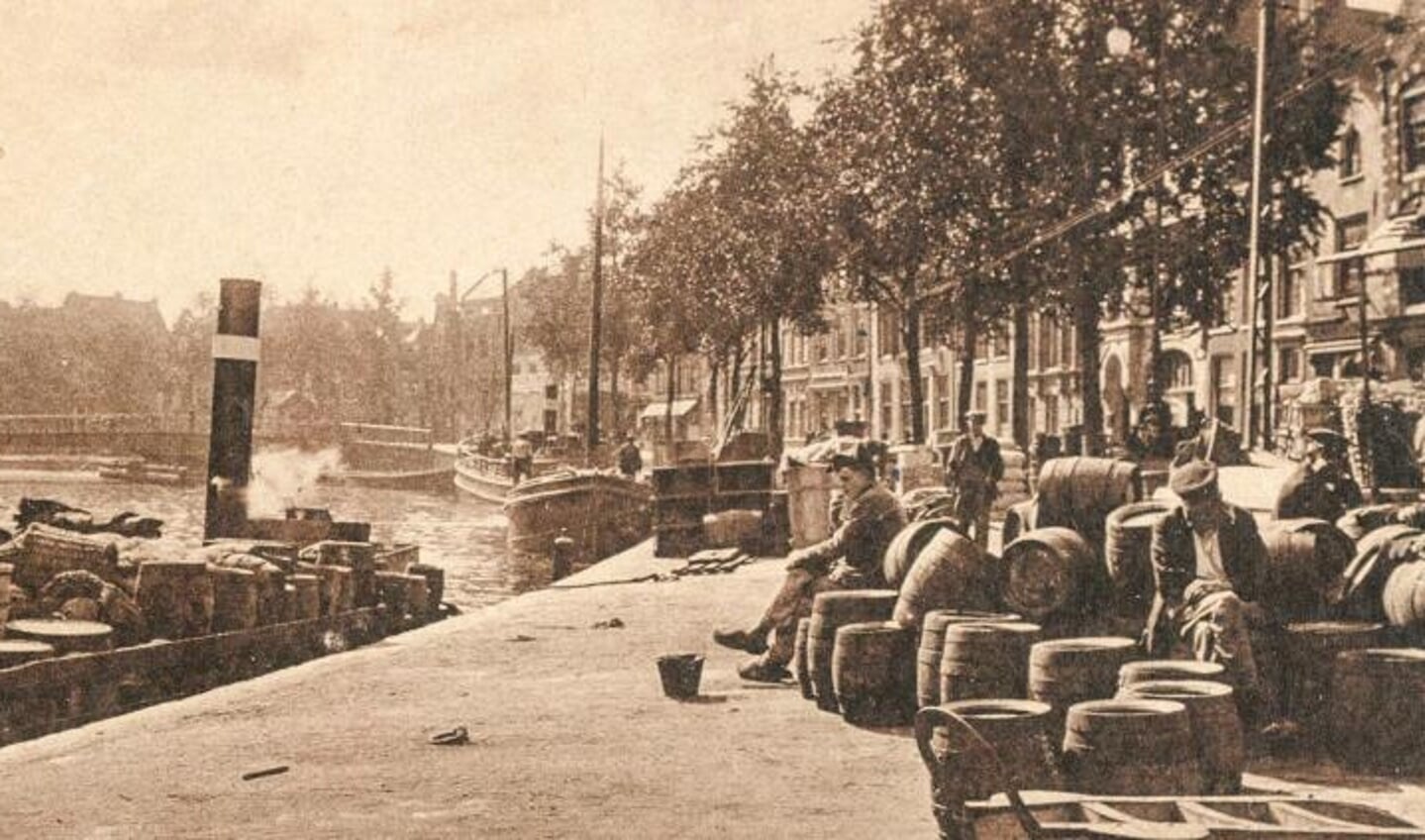 Mannen rusten uit bij het laden en lossen van een schip op het Spaarne.