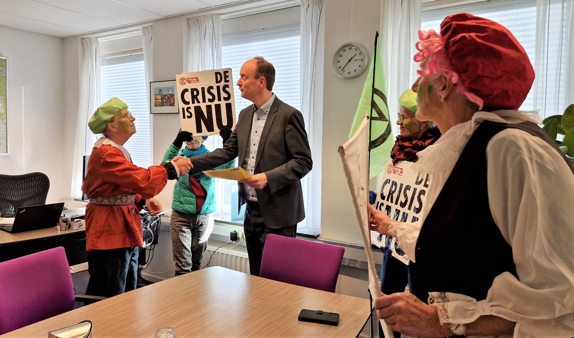 Wethouder Ruitenbeek en Aleid Groothoff schudden elkaar de hand na een onverwacht bezoek van de Groene Pieten van Extinction Rebellion