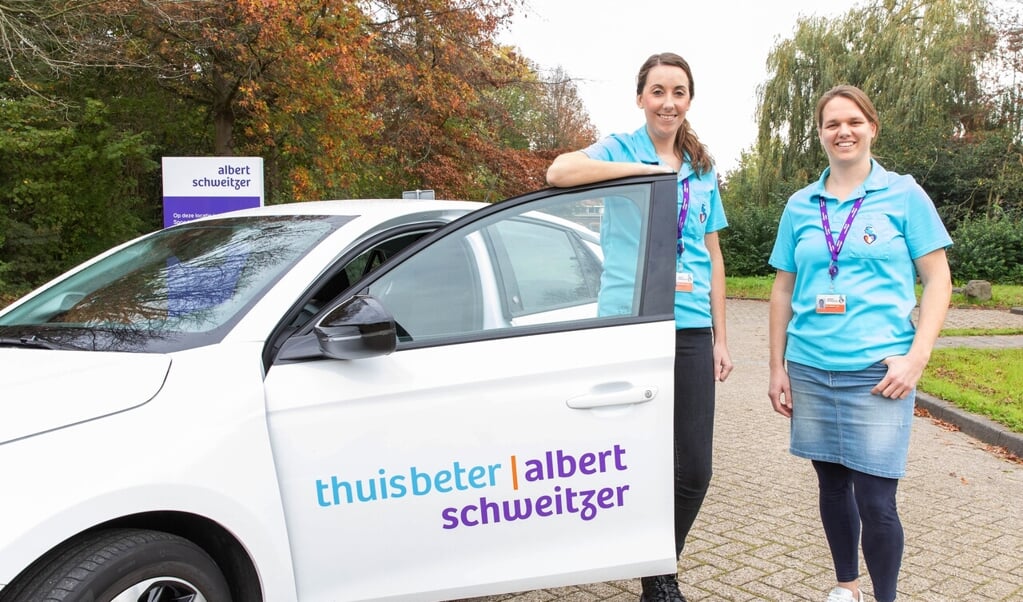 Twee ThuisBeter-verpleegkundigen met een van de auto’s waarmee patiënten worden bezocht.