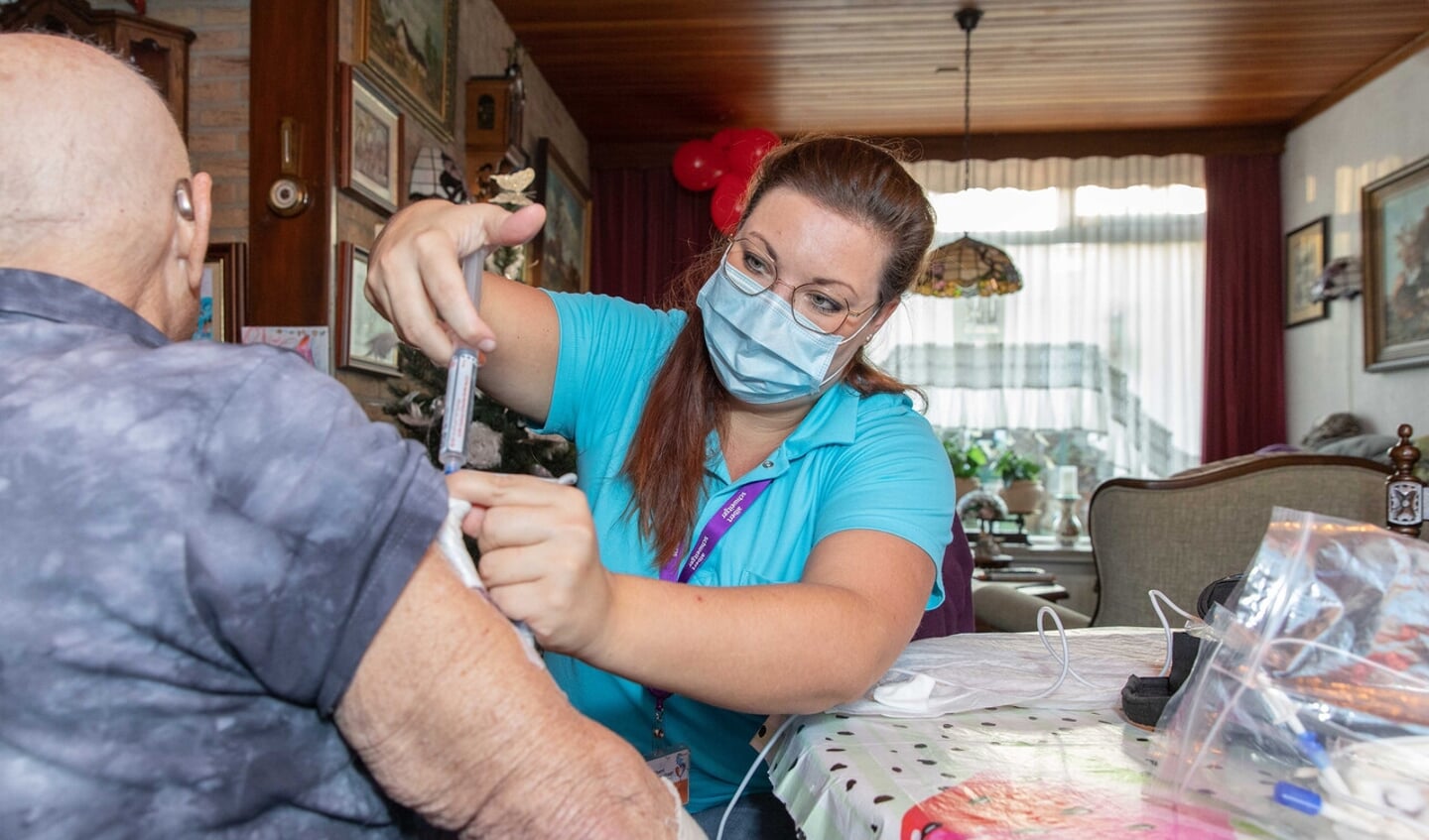 Een verpleegkundige van ThuisBeter dient een patiënt thuis een injectie toe.