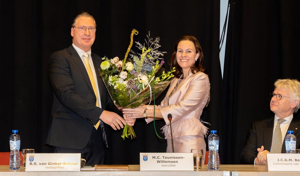 Voorzitter Maarten Zwankhuizen van de vertrouwenscommissie feliciteert burgemeester Marieke Teunissen met een bos bloemen. Commissaris van de Koning John Berends kijkt toe.
