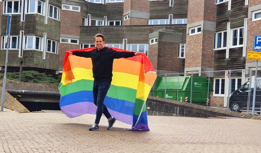 Kandidaat-raadslid Robert Zuidbroek (D66) toont trots de regenboogvlag voor het raadhuis.
