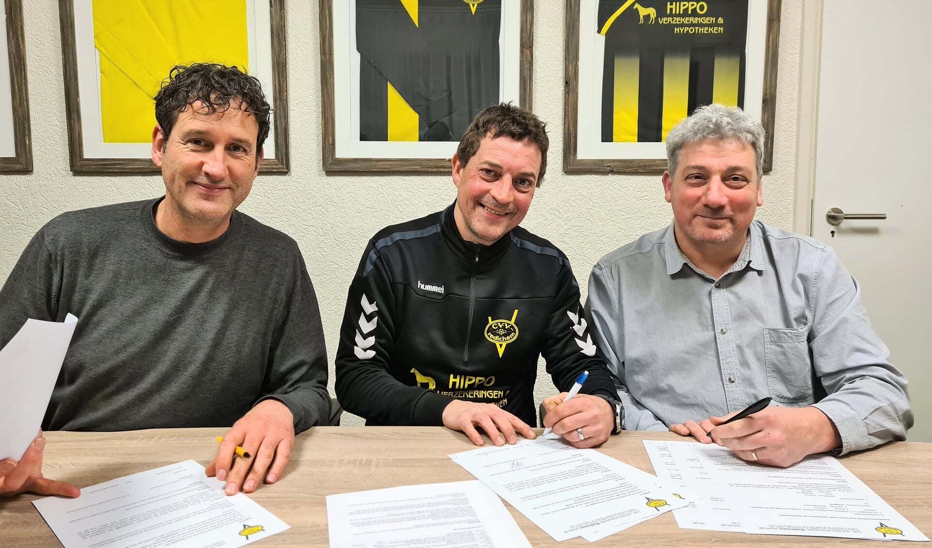 Onder toeziend oog van Redichem-voorzitter Koen Beenen (links) en penningmeester Rini van Ernst (rechts) zet Maarten Kerkhof zijn handtekening onder zijn nieuwe contract.