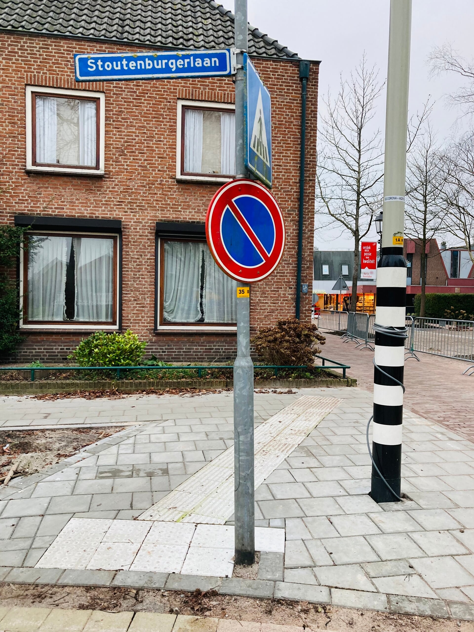 De nieuw aangelegde blindegeleidestrook kwam uit bij een hekje van een hoekhuis en de nieuwe verkeerspaal was op de geleidestrook geplaatst.