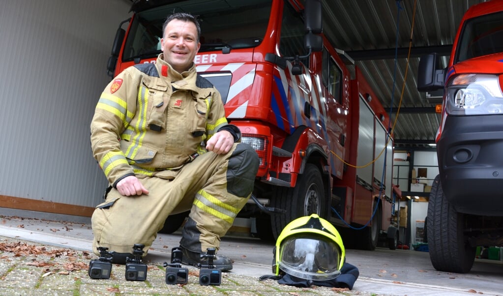 Brandweerman Tom Heebink met voor hem de vier GoPro-actiecamera's. In de brandweerwagen zit nog een vijfde camera.