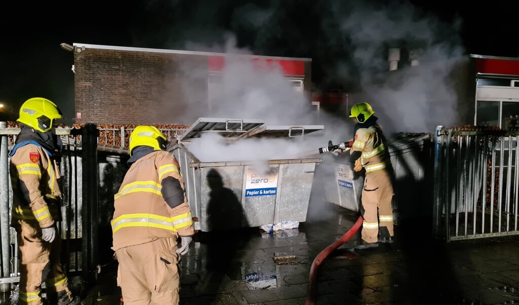 De brandweer blust papiercontainers aan de Buizerdlaan in Nijkerk. 