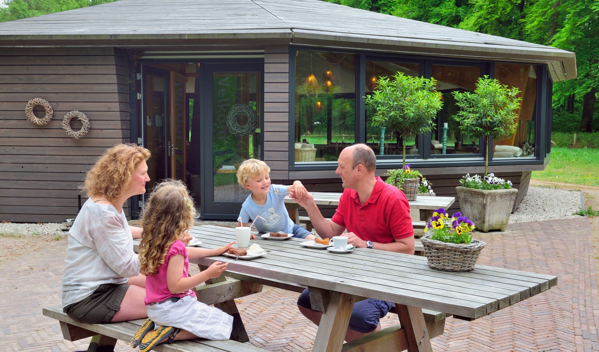 Een vader, moedern en twee kinderen genieten van wat drinken op het terras van theehuis Oud Groevenbeek