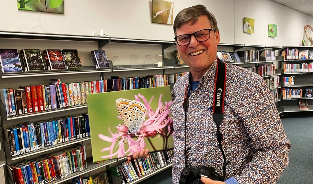 Rob van de Bor met één van zijn foto's van een vlinder, in de bibliotheek in Renswoude.