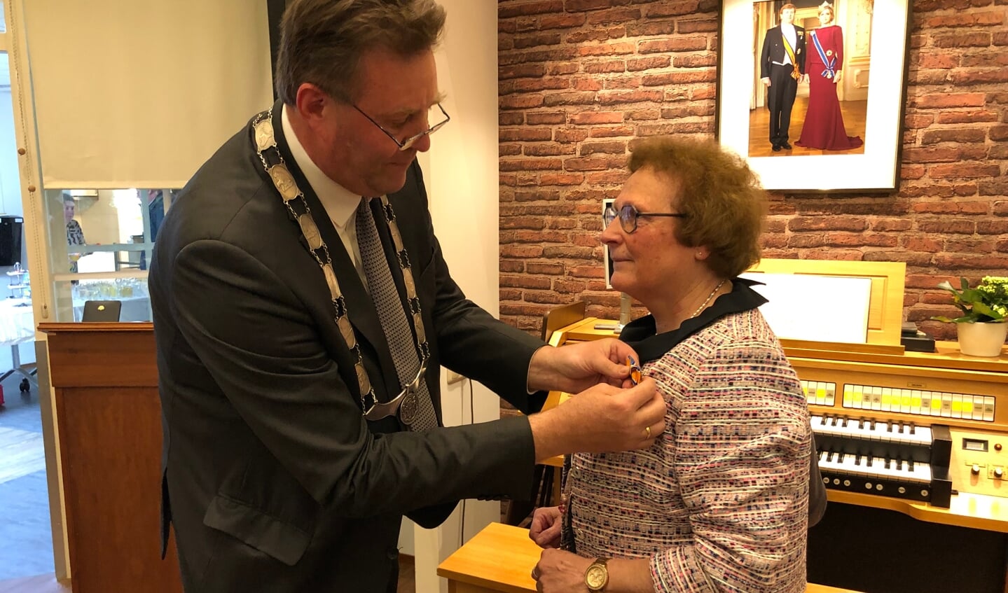 Burgemeester Breunis van de Weerd speldt de koninklijke onderscheiding op bij Cokky de Visser.