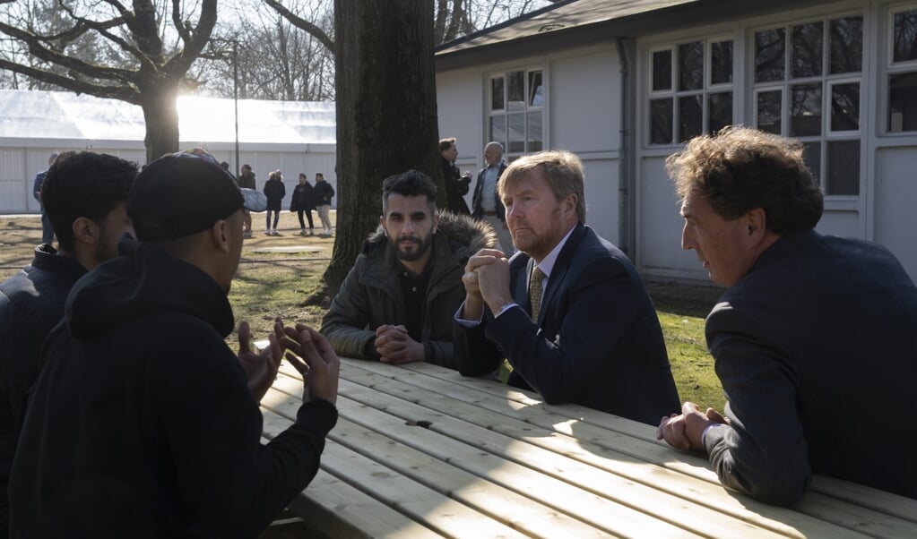Koning Willem-Alexander en burgemeester René Verhulst praten tijdens het koninklijke bezoek met een groepje gevluchte Oekraïners die zijn ondergebracht in legerplaats Harskamp.