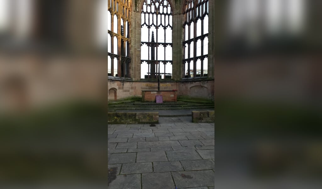 Een deel van de verwoestte Kathedraal van Coventry met de tekst 