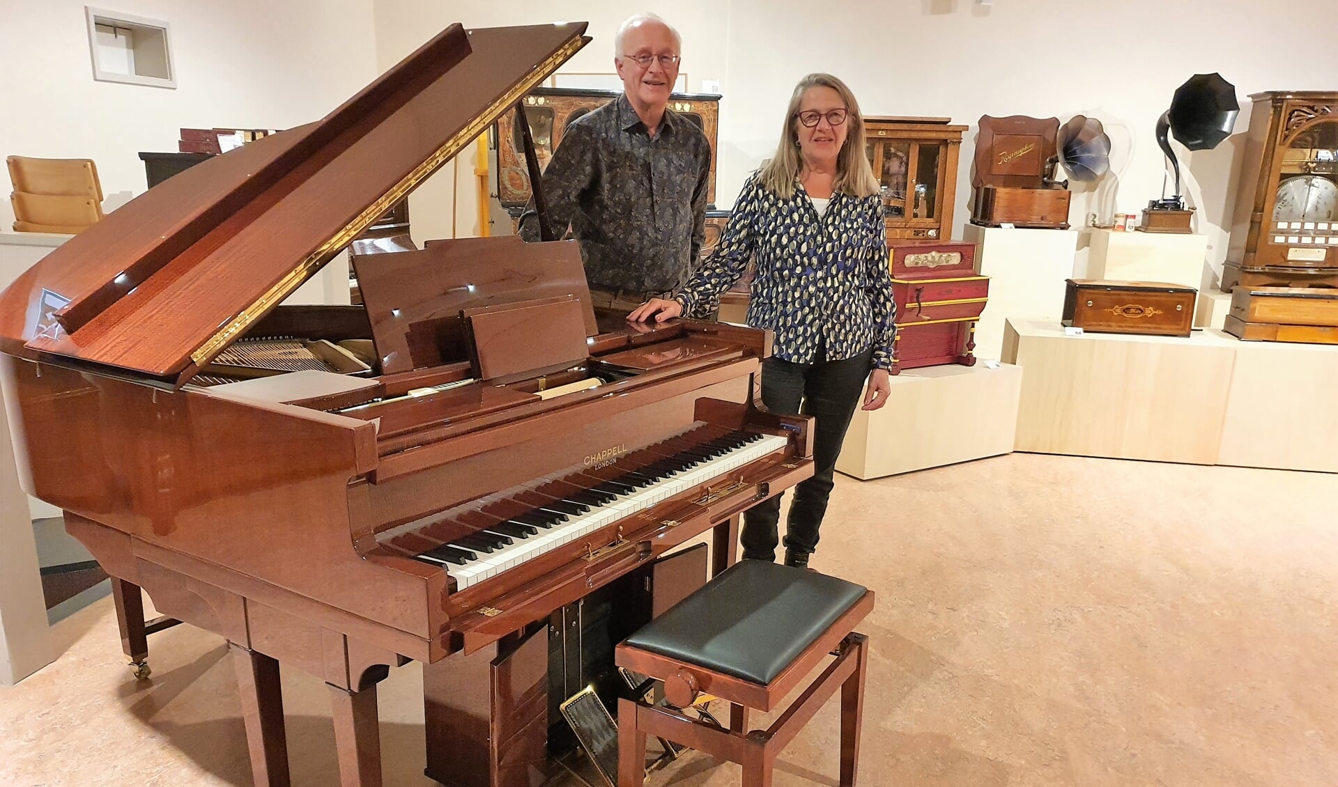 Museumdirecteur Johan van de Pol en de voorzitter van 'de Vrienden' Meta Moerman poseren bij de bijzondere Chapell pianola.