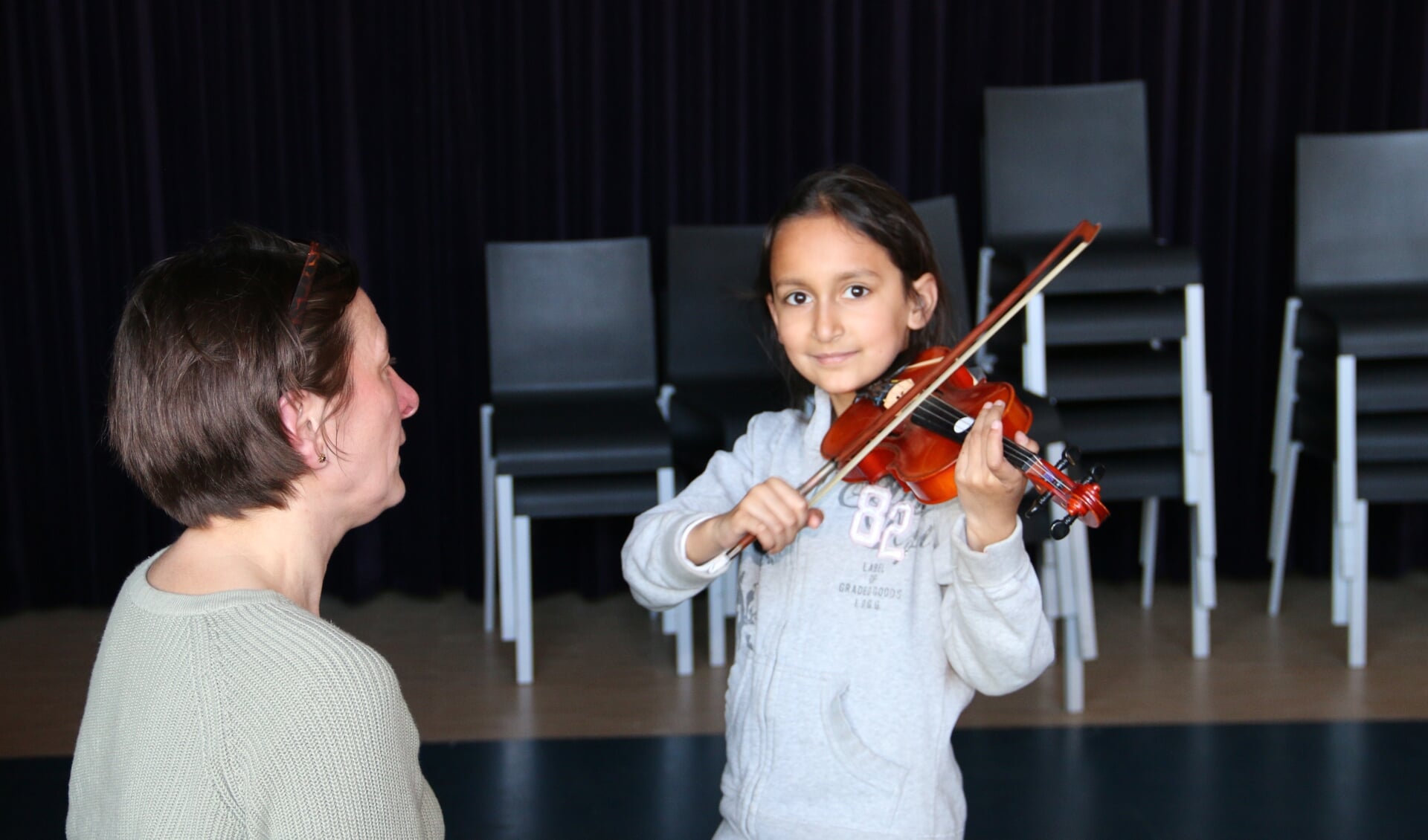 Een jonge bezoeker van de open dag probeert de viool bij docent Heleen Delis.