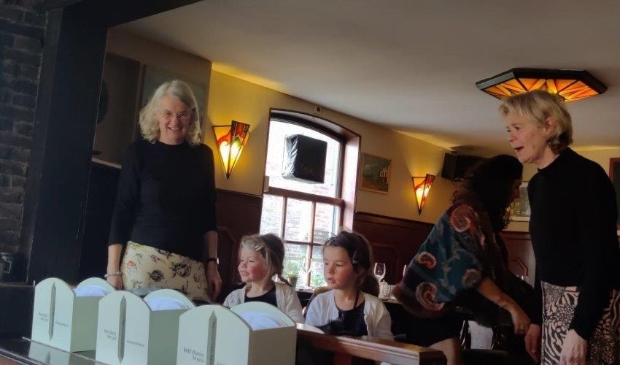 <p>Mathilde de Vriese en Sonja van der Valk presenteren de kaartenbakken samen met de jonge bewoonsters van de hoeve.</p>